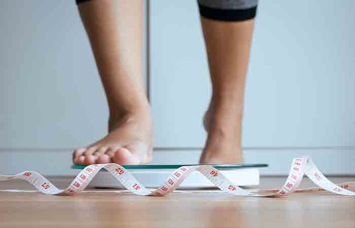 Woman feet getting on scale to check weight gain