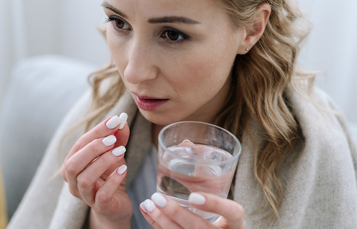 Woman taking antibiotics to get relief from sore throat