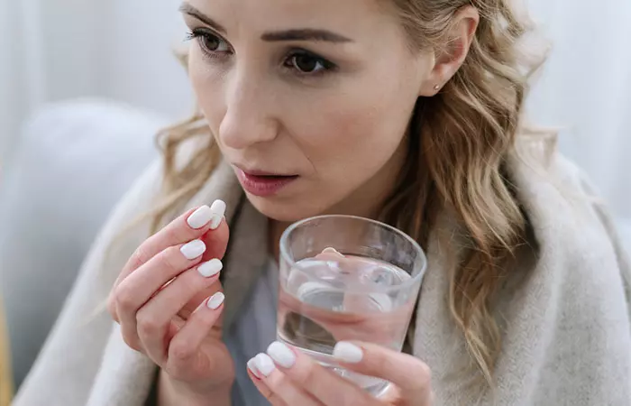 Woman taking antibiotics to get relief from sore throat