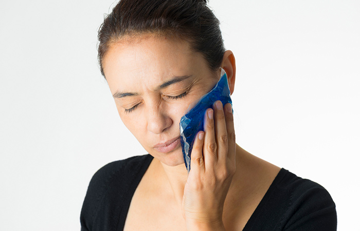 Woman using a cold compress on her face to reduce swelling
