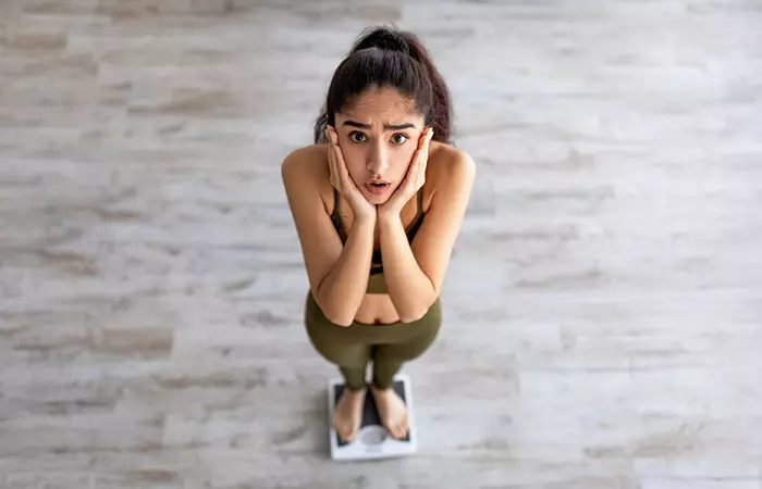 Woman standing on the scale disappointed about her weight loss