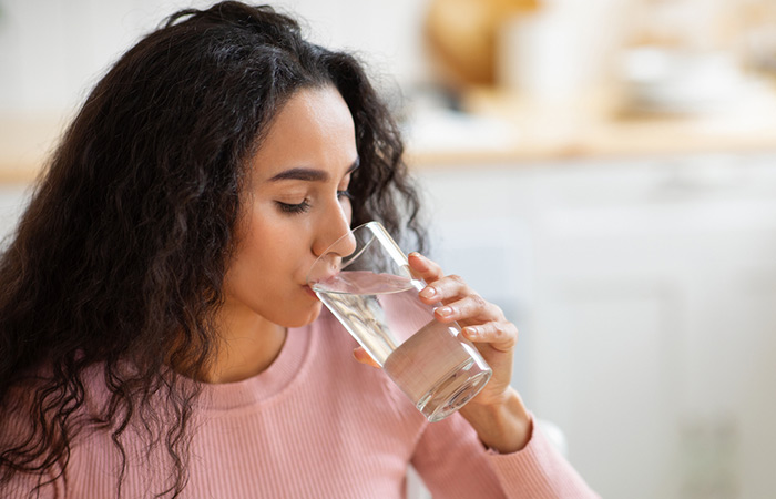 Woman drinking a glass of water to avoid swelling on the face