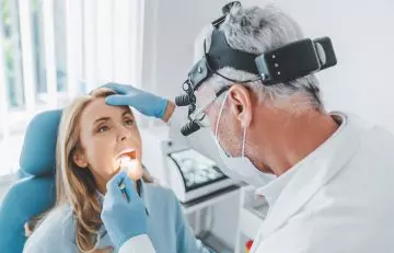 Doctor checking a woman's sore throat