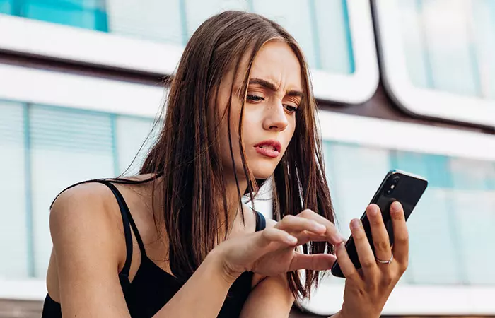 Woman looking at phone feeling confused and worried 