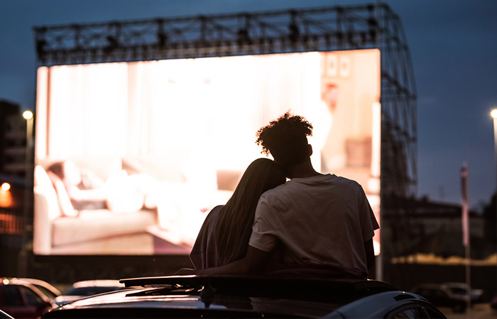 A romantic couple on an outdoor date watching a drive-in movie