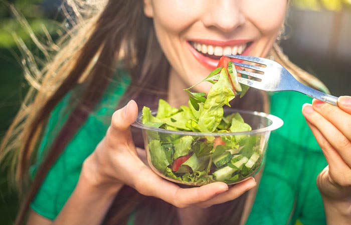 Closeup of a woman eating leafy vegetables for magnesium
