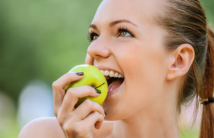 Woman eating green apple on keto as it is a low carb fruit
