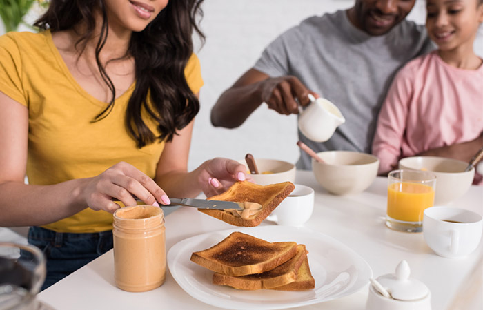 A woman is having toast with peanut butter for weight gain
