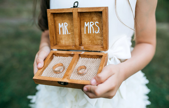 A girl carrying a beautiful box with rings under a Mr. and Mrs. sign
