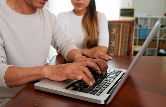 Closeup of couple working on a laptop sending RSVP