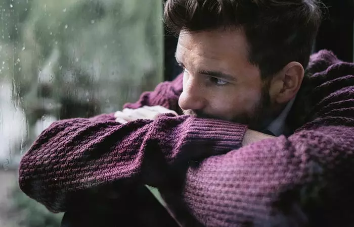 Solemn and emotional man looking out of window