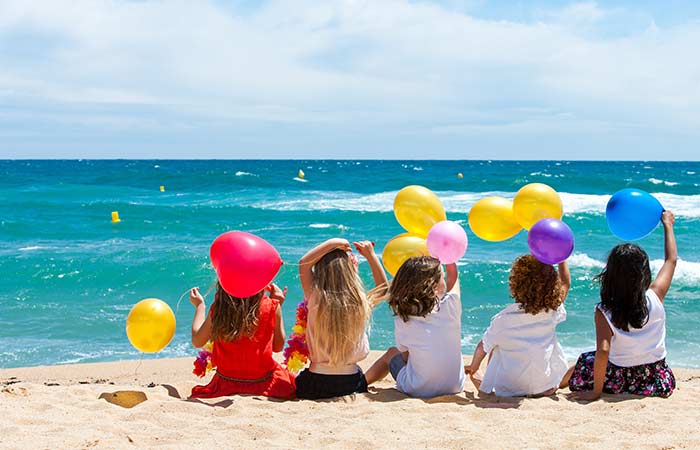 Kids holding colorful balloons enjoying the beach birthday party