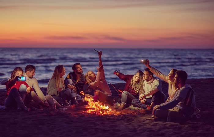 a group of friends enjoying a bonfire party on the beach