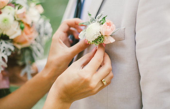 Bride putting on a DIY boutonniere on her groom
