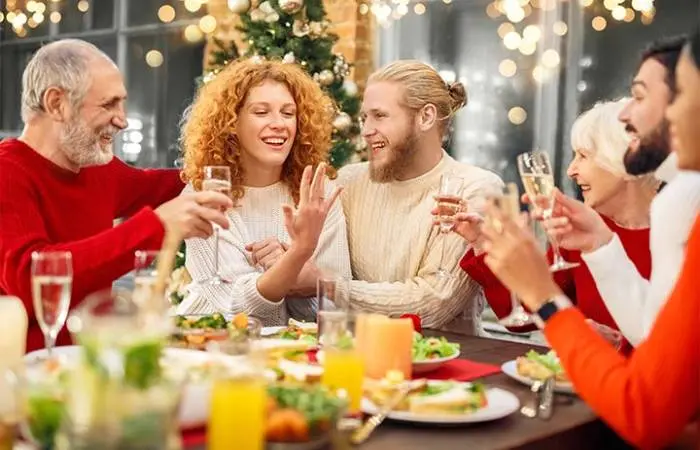 A newly engaged couple at the dinner table with friends and family