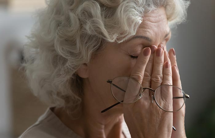 Old woman rubbing her dry eyelids
