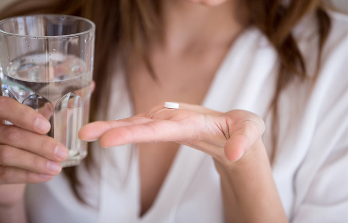 Woman taking prescribed antibiotic pill to treat vaginal boils