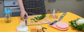 Woman cutting cucumbers to make juice