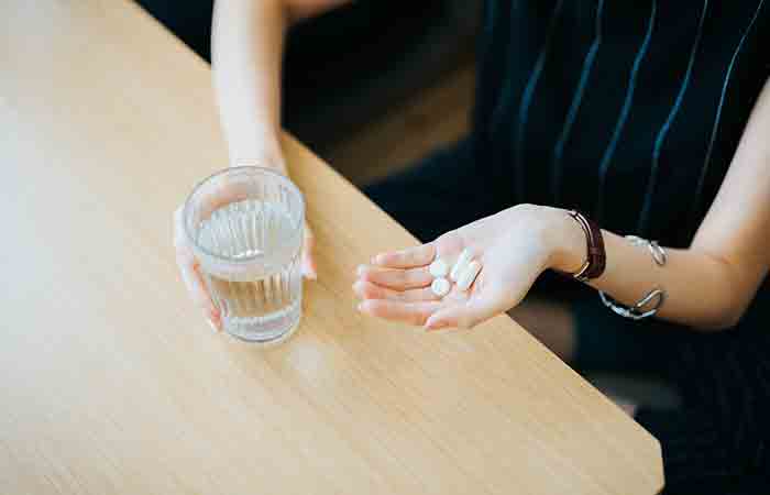 Woman holding a glass of water and medicines