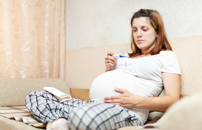 Femeia însărcinată răcită își verifică temperatura