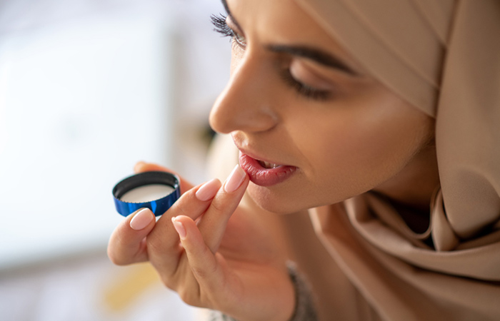 Woman applying lip balm to lighten dark lips