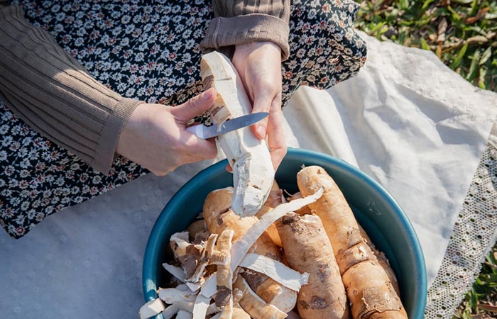 Woman peeling cassava roots to make flour out of it