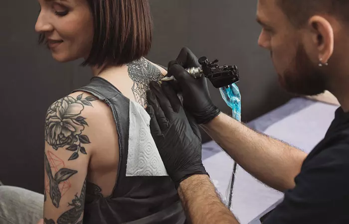 A professional tattoo artist making a tattoo on a woman's back