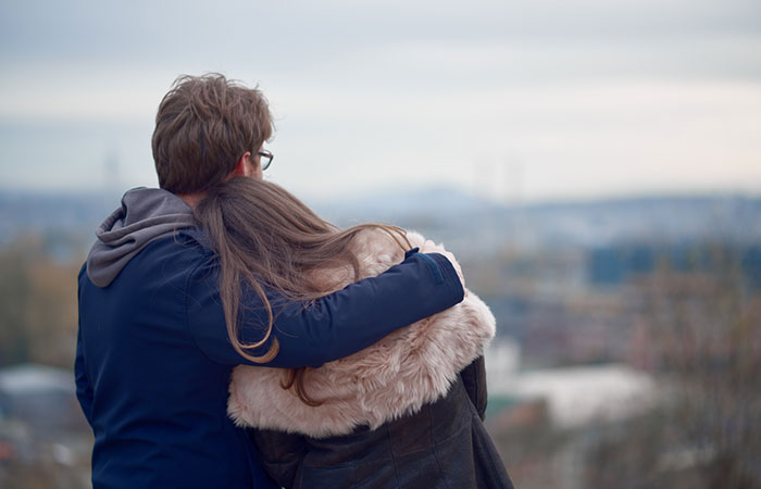 An accepting couple hugging and looking at the horizon