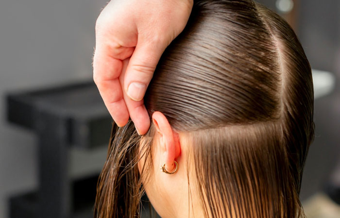 Hairdresser dividing woman's hair into sections for perming