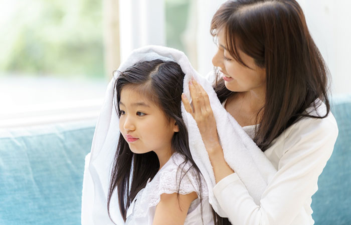 Mother drying girl's hair with a soft towel 