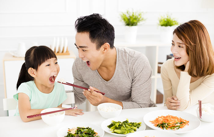 Parents feeding their daughter to fulfill their parental responsibility