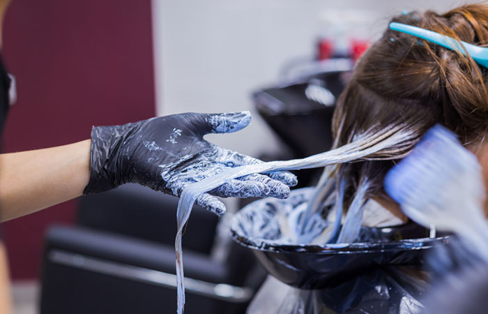 Salon stylist performing cellophane hair treatment on client
