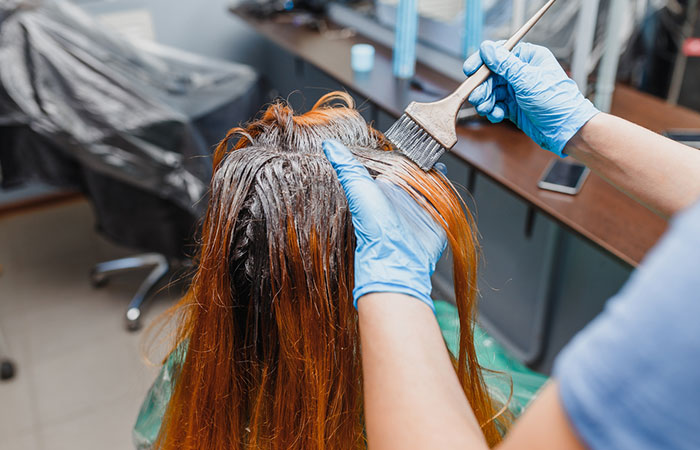 Salon stylist performing cellophane hair treatment on client