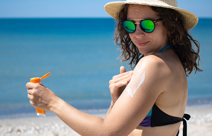 Woman applying SPF cream with baby oil to get tanned
