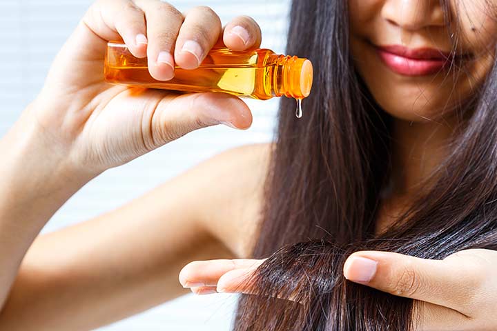 Woman applying camellia oil to prevent hair damage
