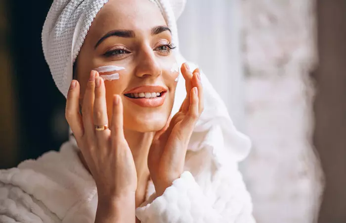 Woman applying face cream with balck seed oil