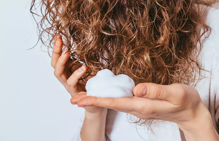 Woman applying hair mousse