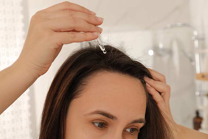Woman applying hair serum containing camellia oil