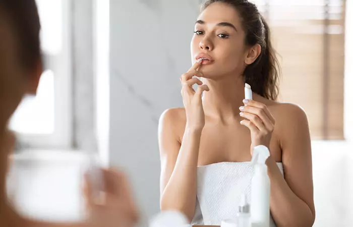 Woman applying lip balm to prevent skin tags