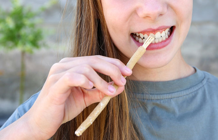 Woman cleaning her teeth with miswak brush