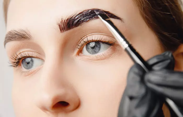 Woman darkening eyebrows with a dye