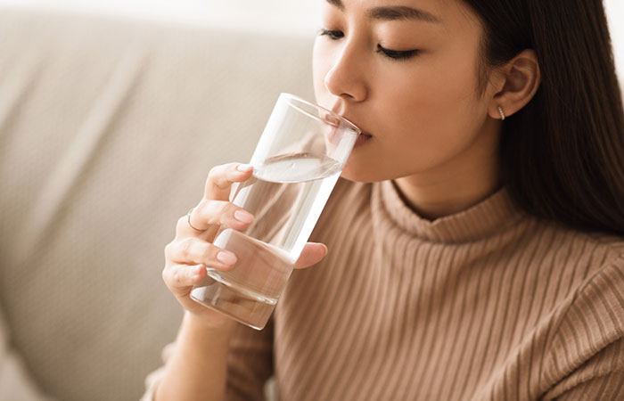 Woman drinking water to reduce stretch marks 