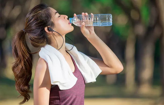 Woman drinking water to stay hydrated and reduce body pain.