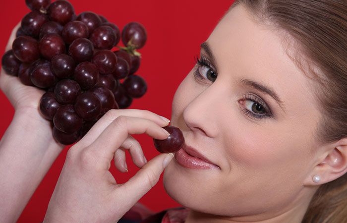 Woman eating red grapes to flush kidneys naturally