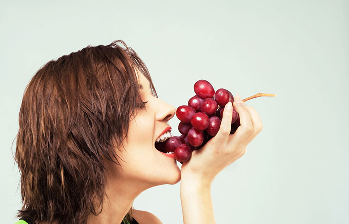 Woman eats red grapes for radiant skin