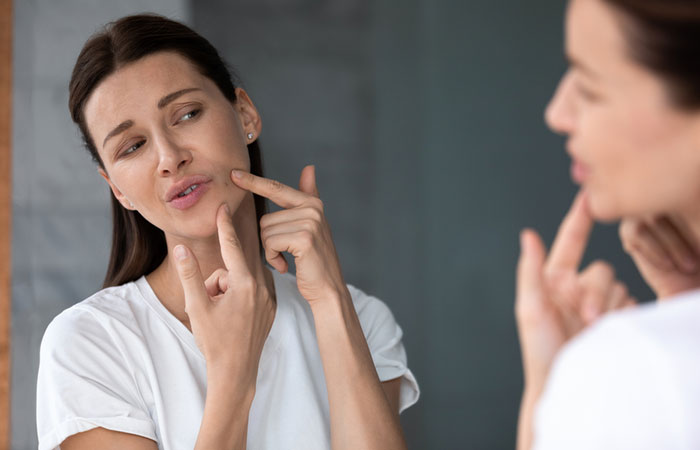 Woman examining her blemishes in the mirror may benefit from salt water.
