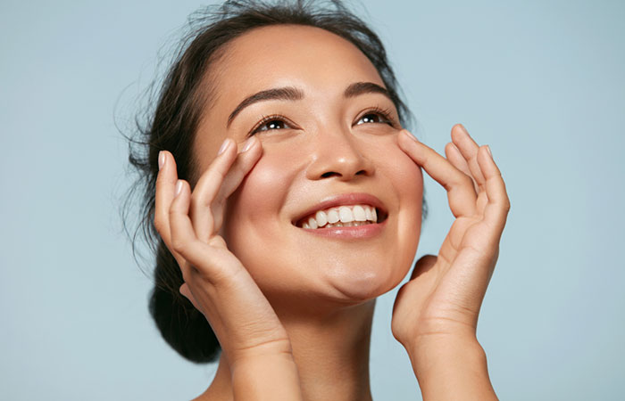 Woman happily touching her radiant skin as a potential benefit of asafoetida