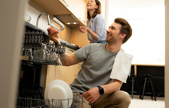 Woman helps man load the dishwasher as a sign of supporting him
