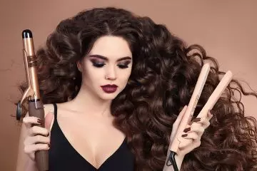 Woman holding a curling iron and a flat iron