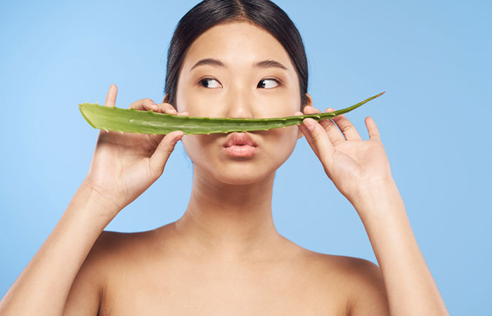Woman holding an aloe vera leaf as a moustache